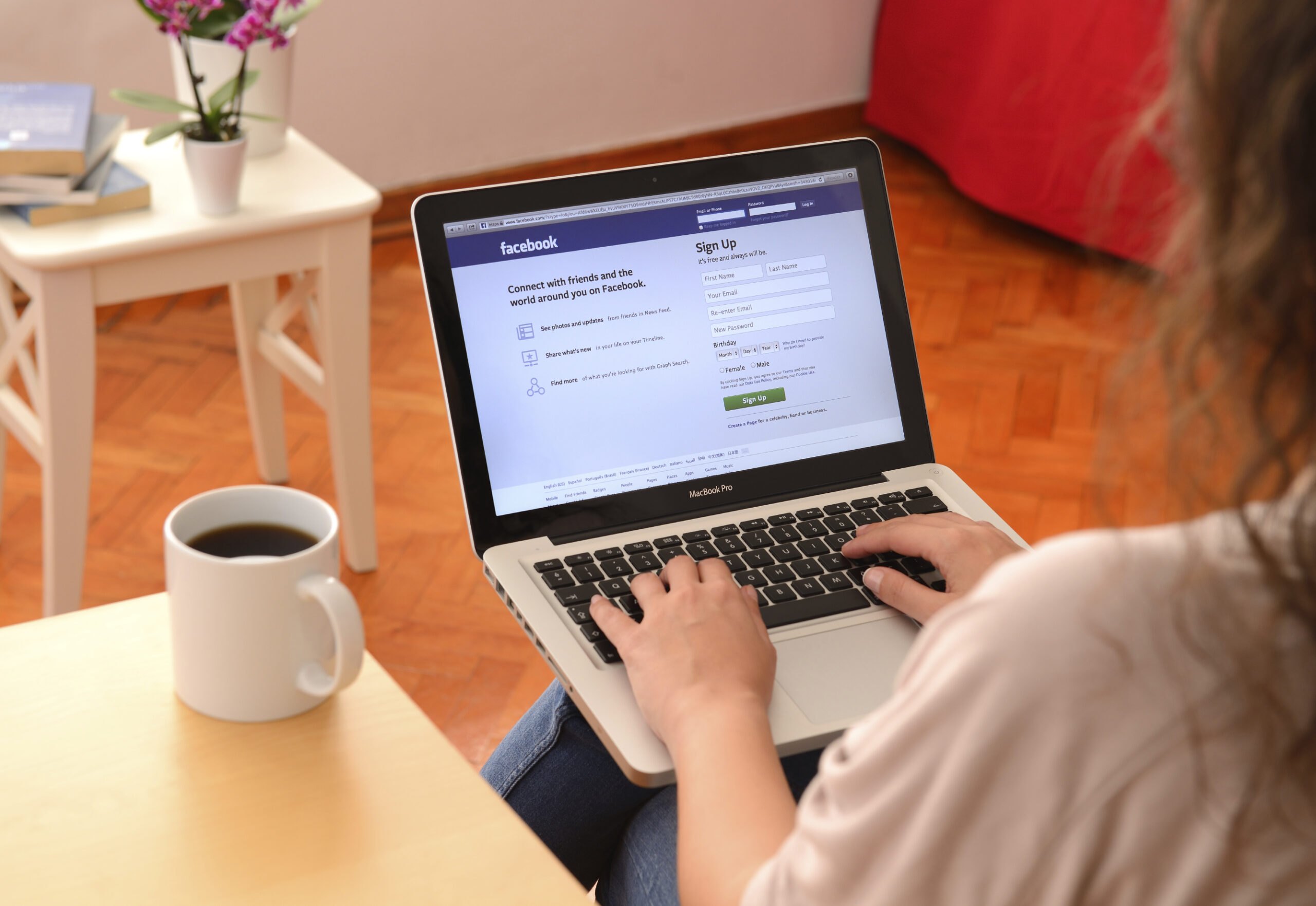 Over shoulder view of woman using Facebook on a laptop computer. (stock image)