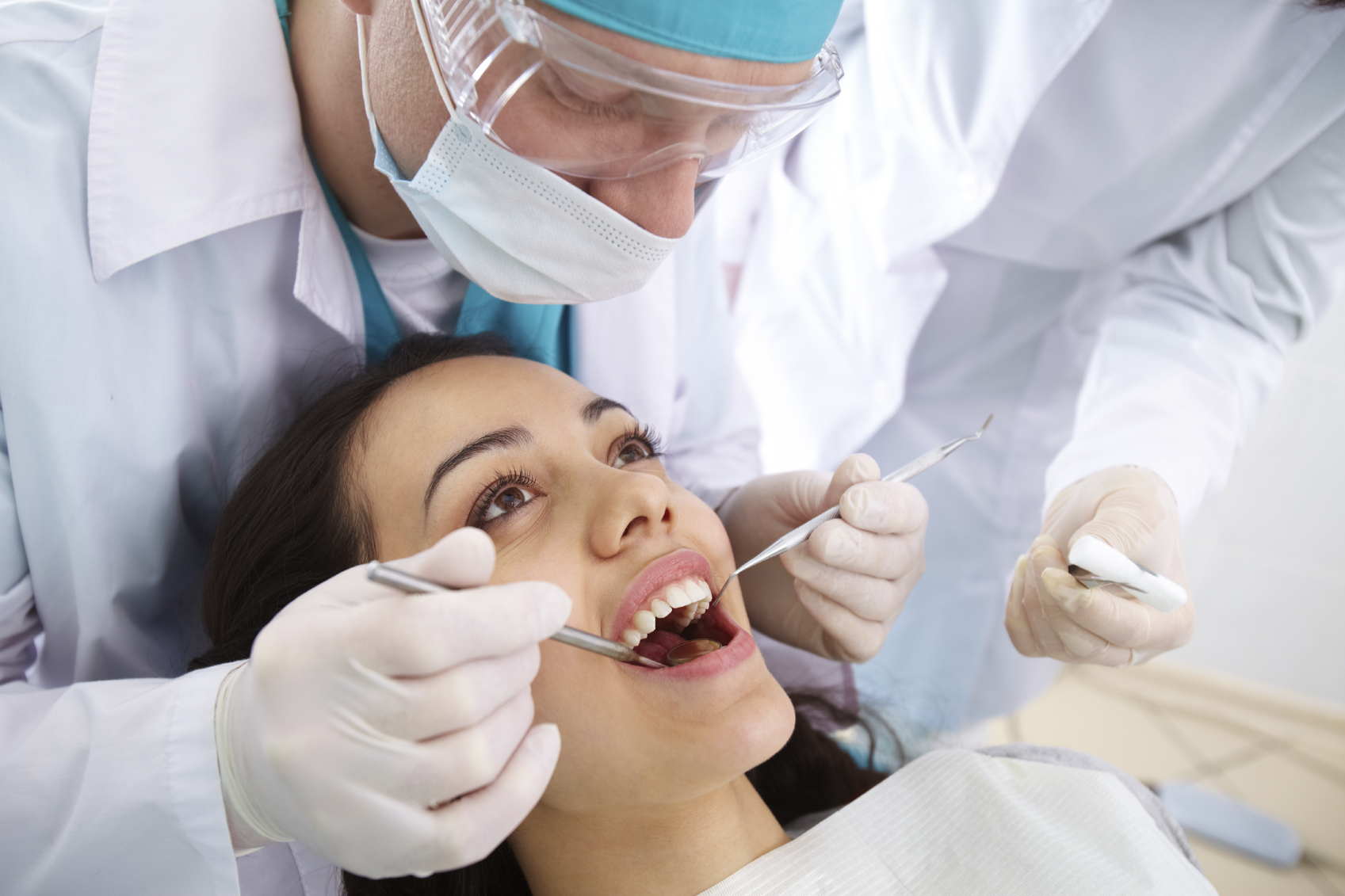 A dentist performs an oral exam on a female patient. (stock image)