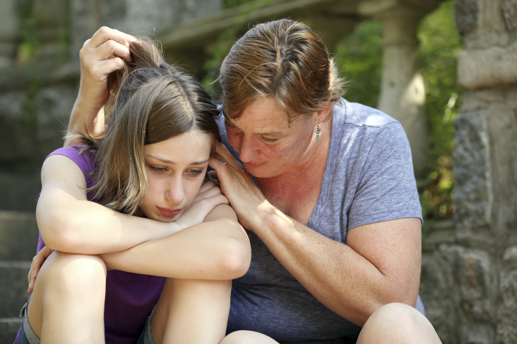 Mother consoling dejected daughter. (stock image)
