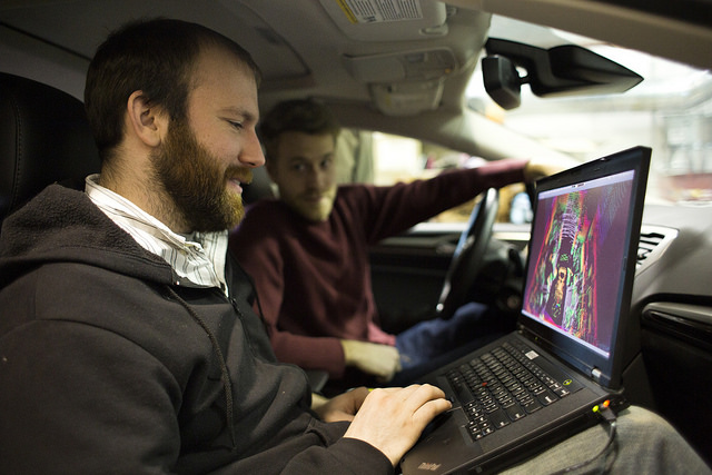 Schuyler Cohen, Engineer in Research, and Ryan Wolcott, Computer Science & Eng PhD Student, discuss the false-color map system generated by the new Automated Ford Fusion. Image credit: Joseph Xu