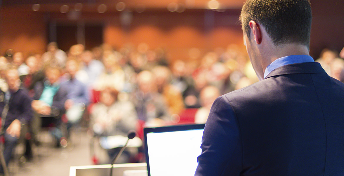A man presents to an audience. (stock image)