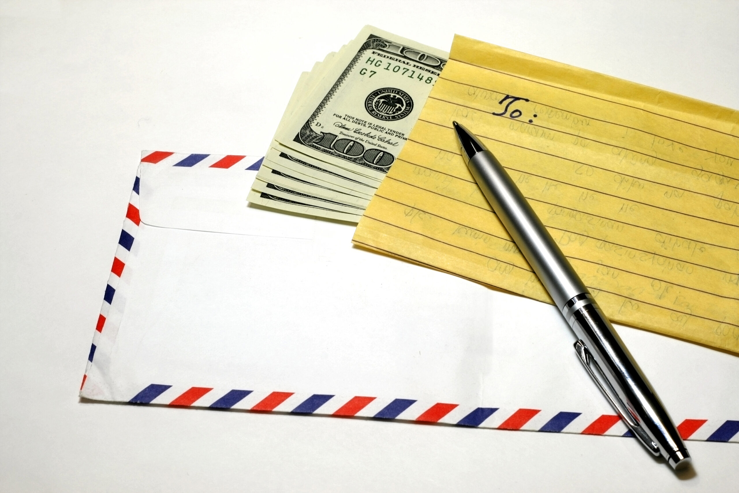 An envelope, note, pen, and cash. (stock image)