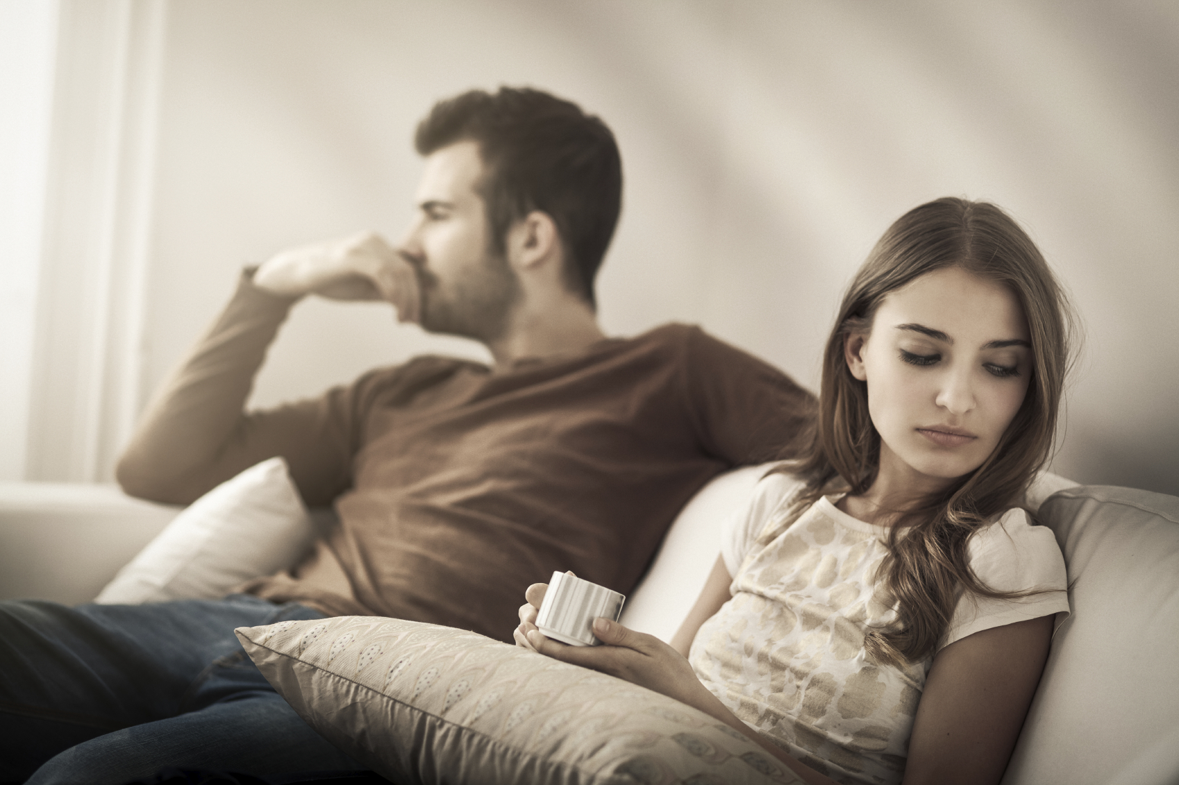 A man and woman sit facing away from each other. (stock image)