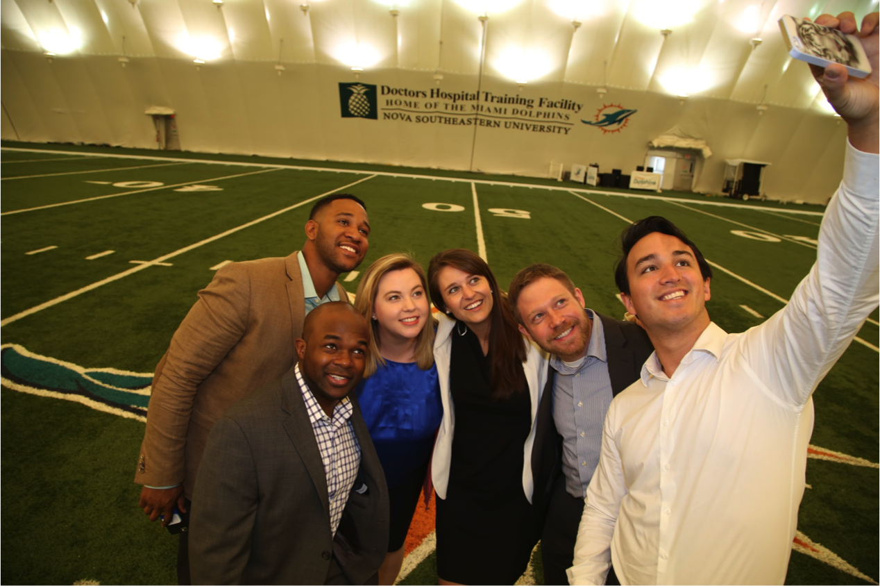 University of Michigan Ross MBA students take a selfie on the 50-yard line at the Miami Dolphins training facility in Davie, Fla., L-R: C.J. Azubuine (foreground), Darryl Tricksey, Aimee Grimshaw, Alexa Likens, Jeffrey Gross and John Thompson. Image credit: Angel Valentin