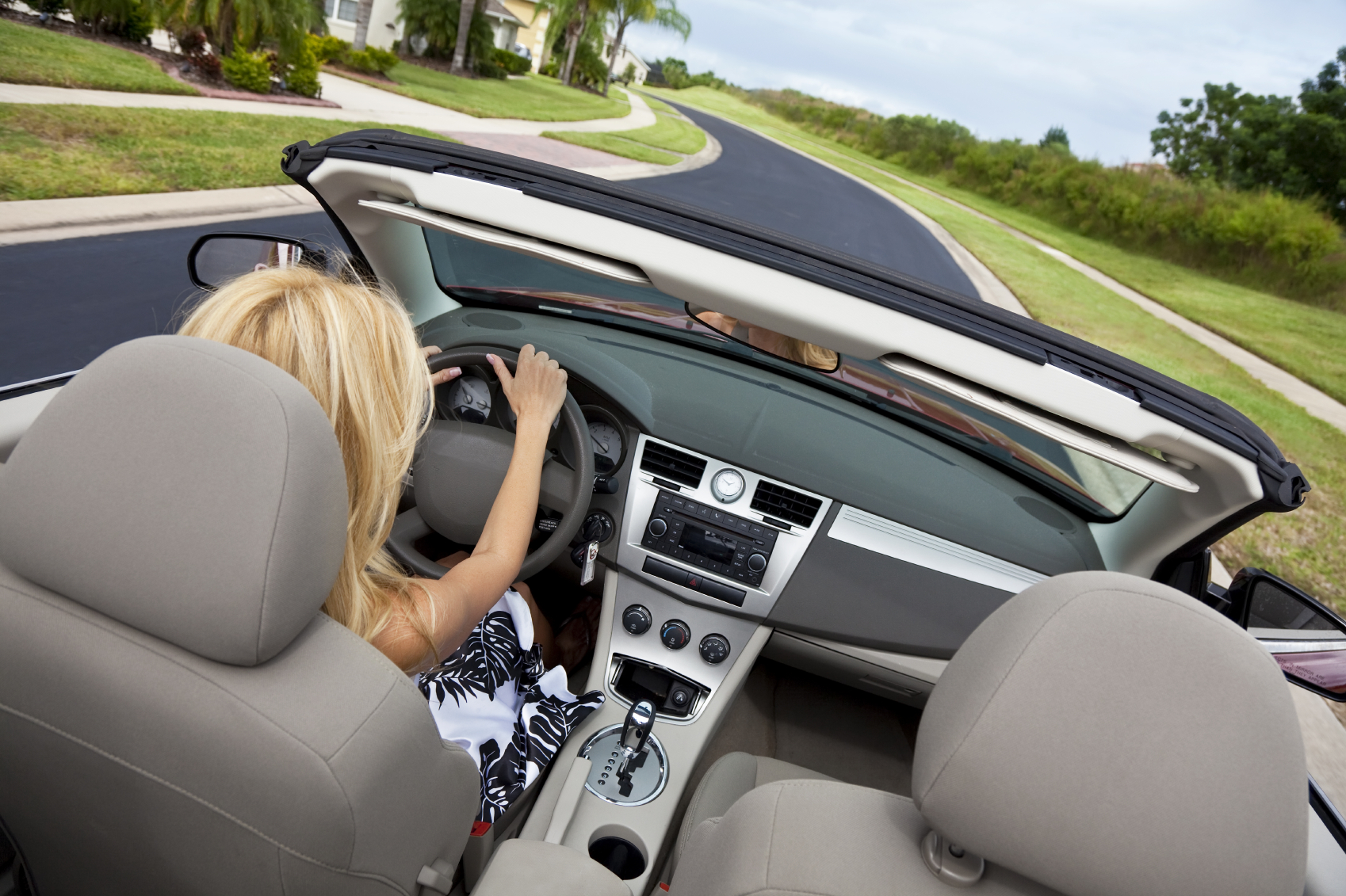 Over the shoulder view of a woman driving a convertable car. (stock image)