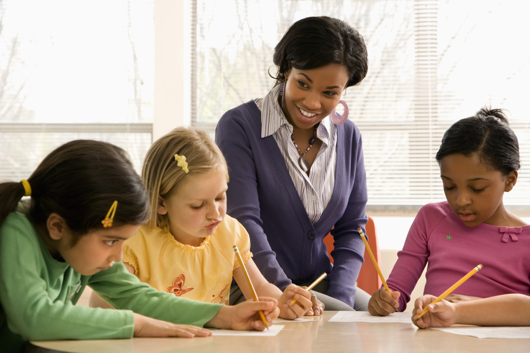 A student collaborating with elementary school students. (stock image)
