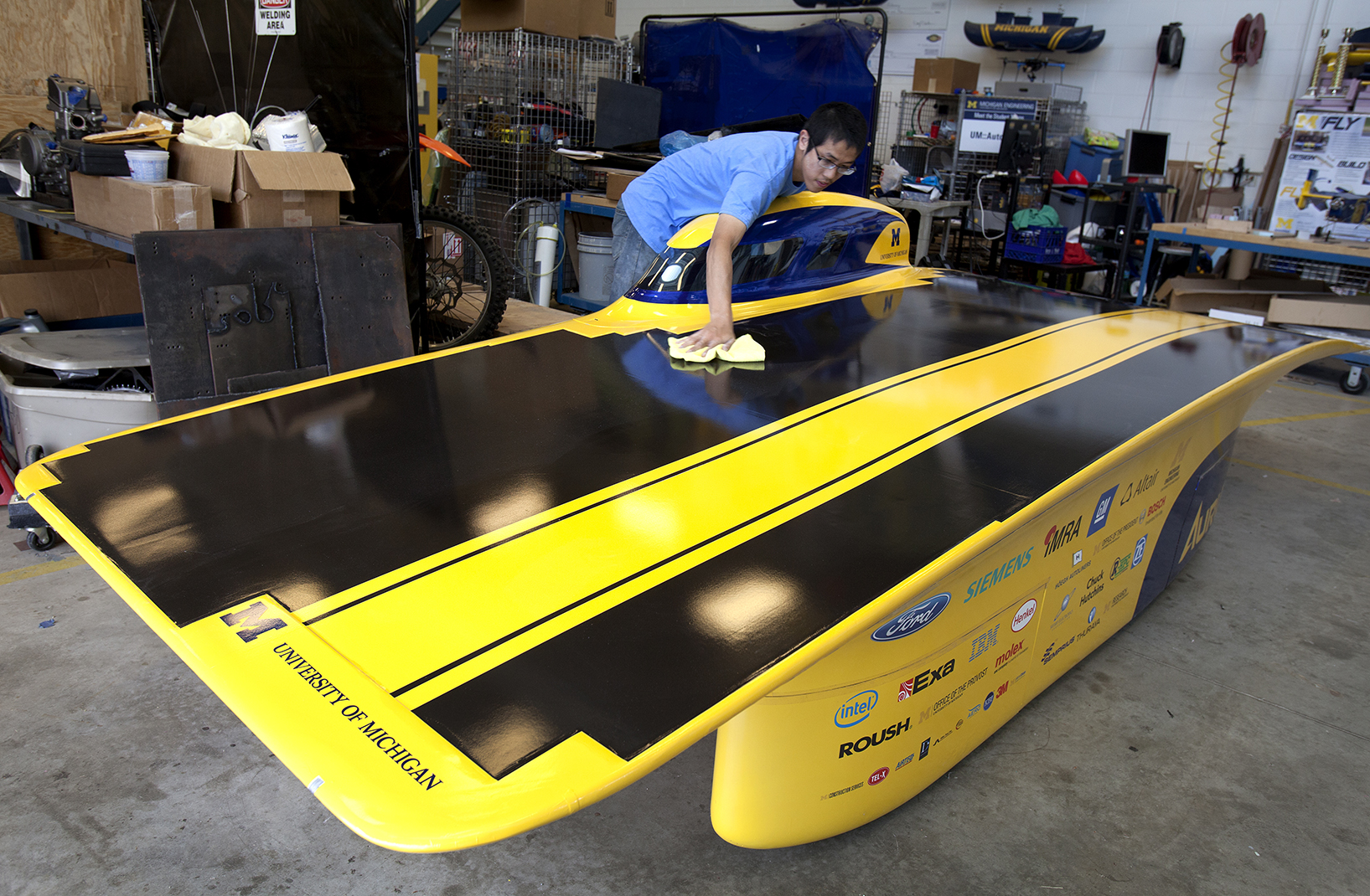 Jiahong Min wipes off dust from the new solar car. He is among the University of Michigan Solar Car team members putting final touches on the car. Image credit: Marcin Szczepanski, Michigan Engineering