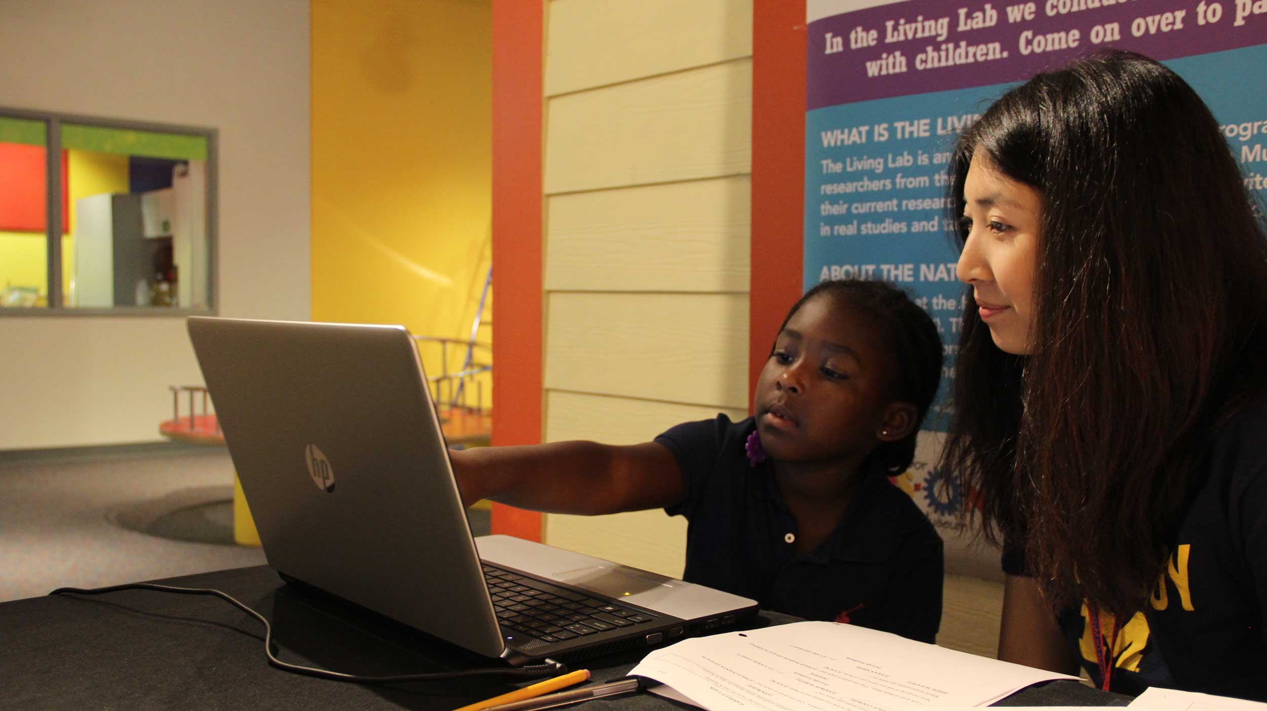 Children visiting the Ann Arbor Hands-On Museum, like 5-year-old Lindsay Bennett from Detroit, can participate in research through the U-M Living Lab. Psychology student Coral Lu is asking Lindsay questions about the cost of items to gauge her understanding of supply and demand. Image credit: Levi Stroud