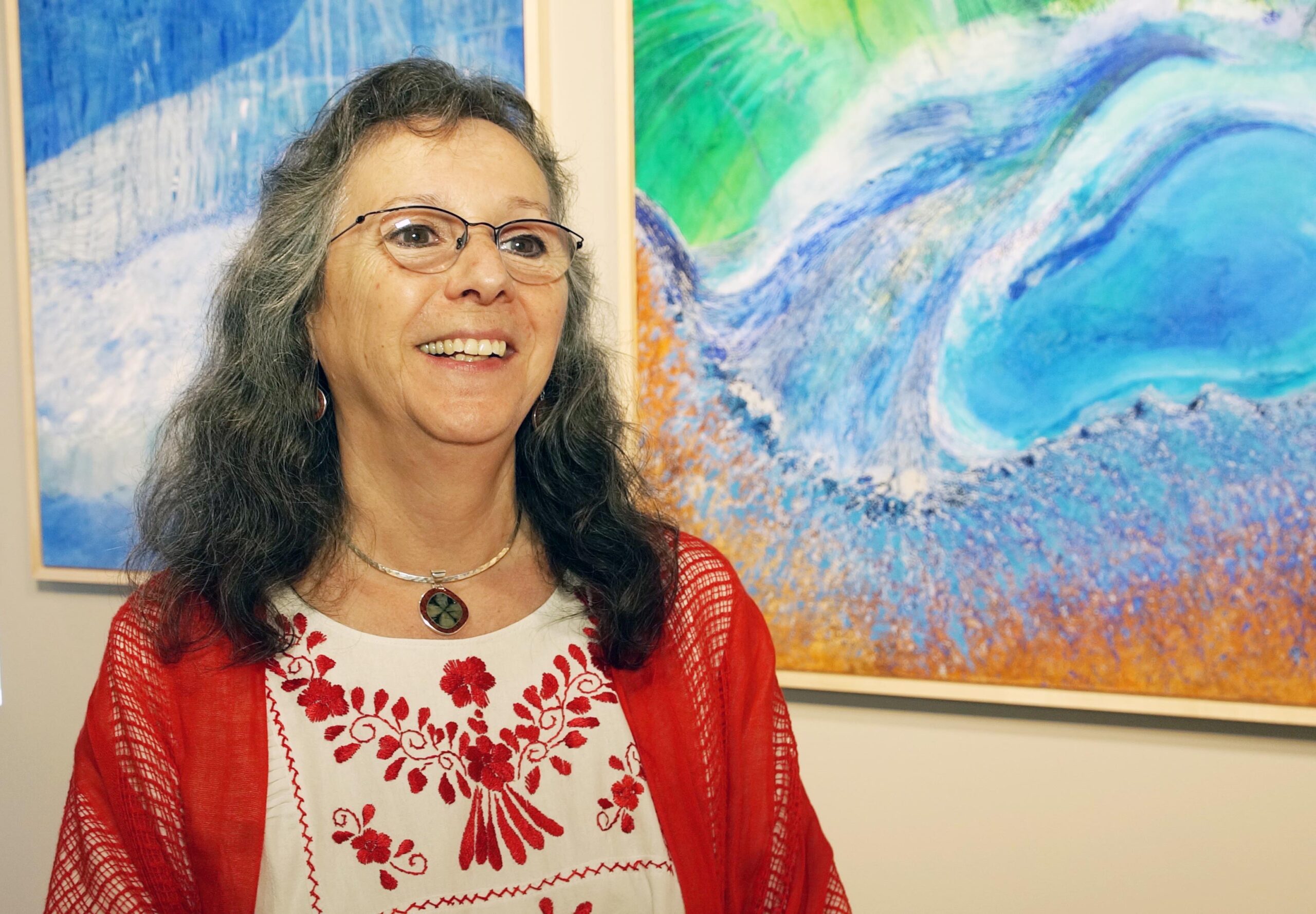 Sara Adlerstein-Gonzalez next to two of her paintings during her recent exhibit at WSG Gallery in downtown Ann Arbor. Image credit: Mike Wood