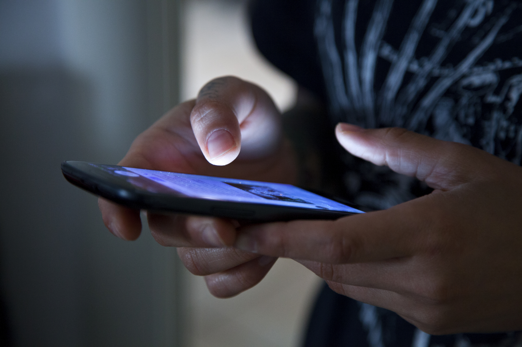 A pair of hands holding a glowing phone. (stock image)