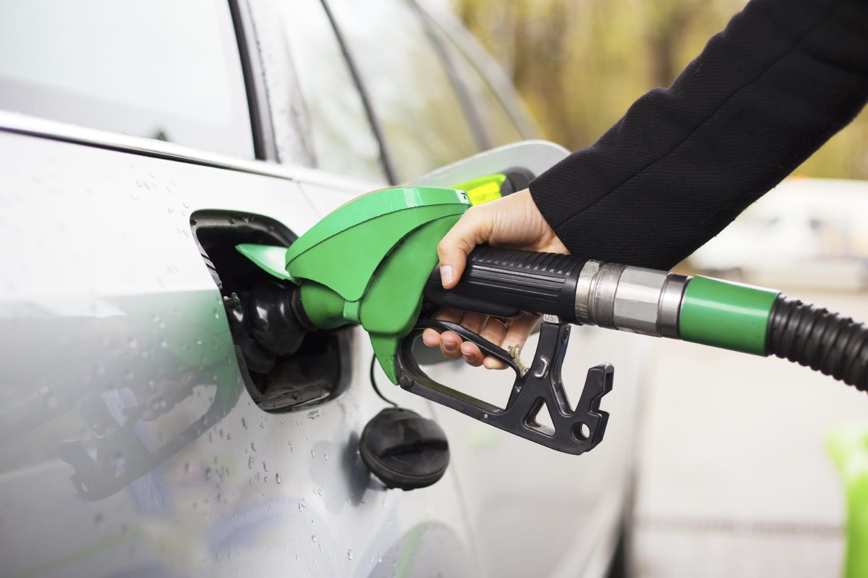 Hand holding fuel pump and refilling car at petrol station. (stock image)