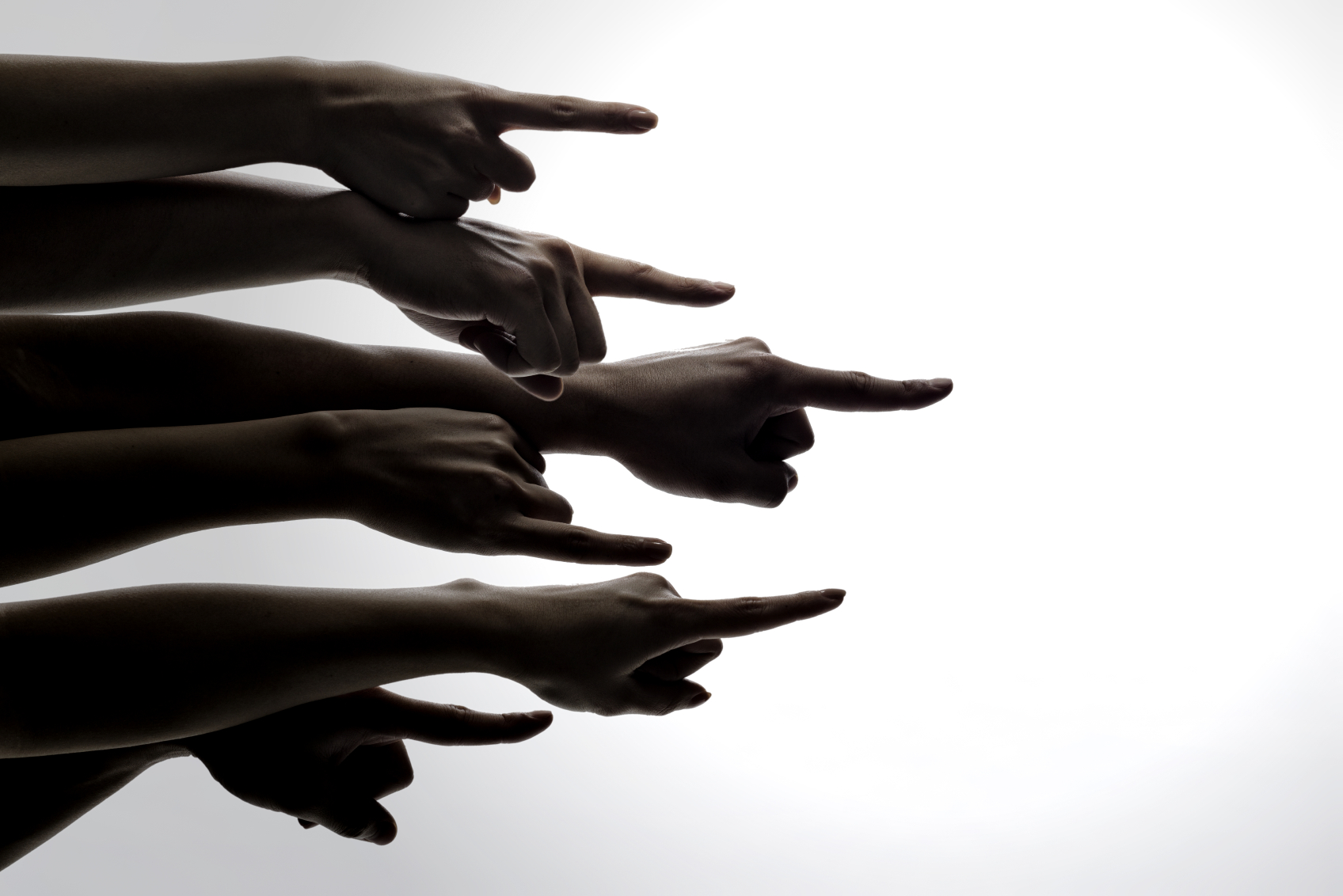 A group of hands point at someone outside of the frame. (stock image)