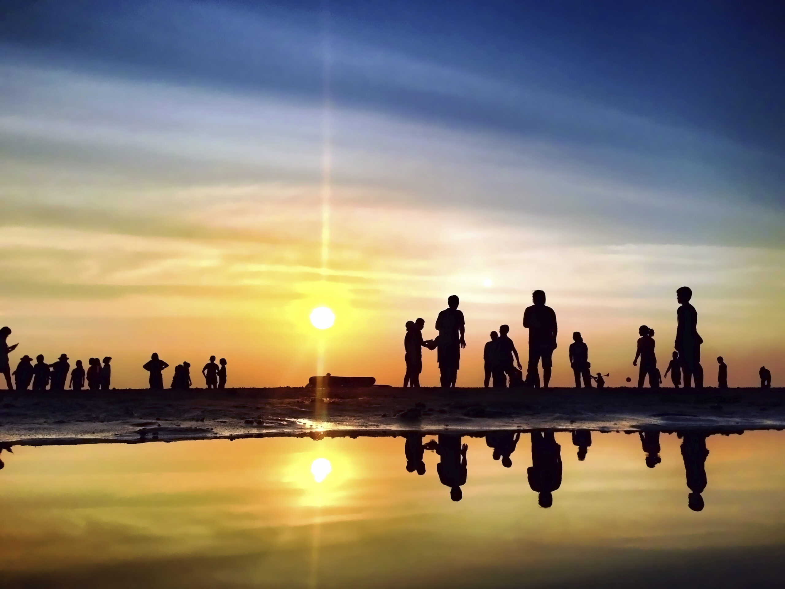 Silhouette of several people on a beach at sunset. (stock image)