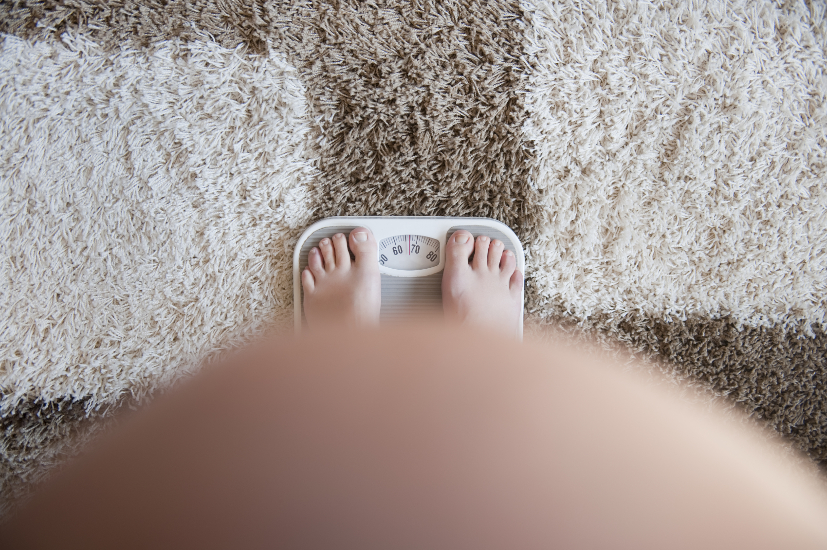 A pregnant woman stands on a scale. (stock image)