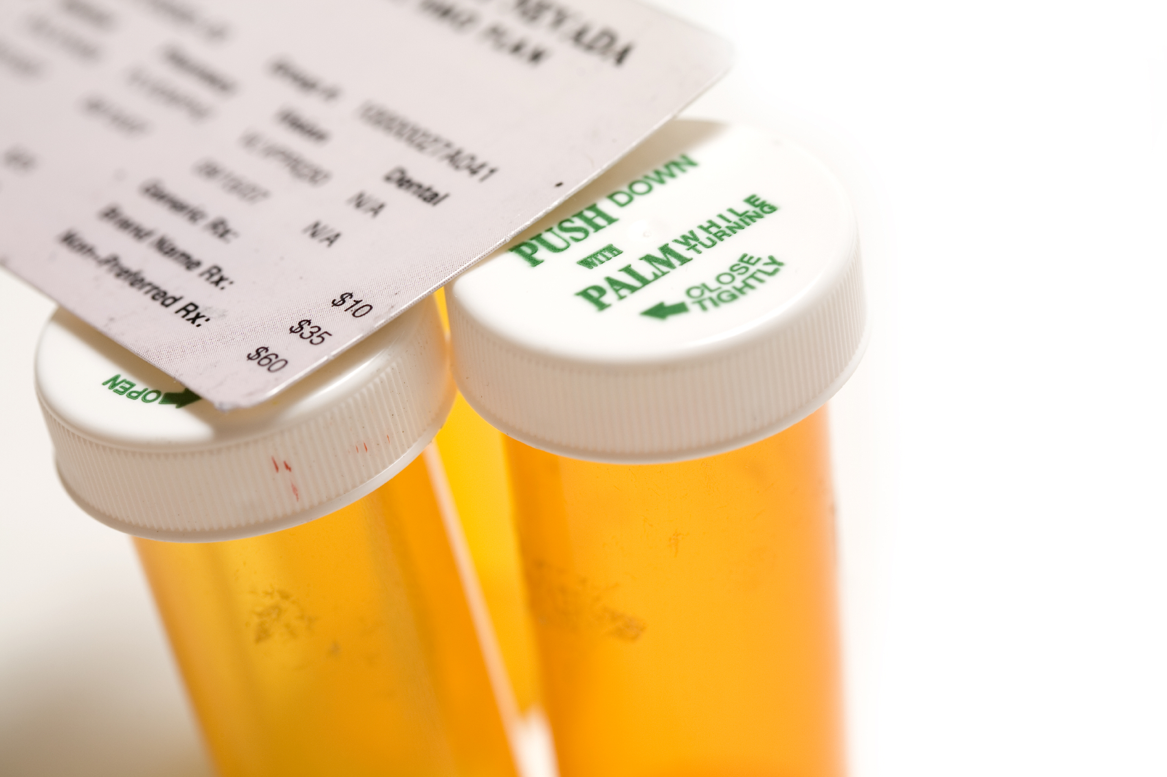 An insurance card sits atop several prescription bottles. (stock image)