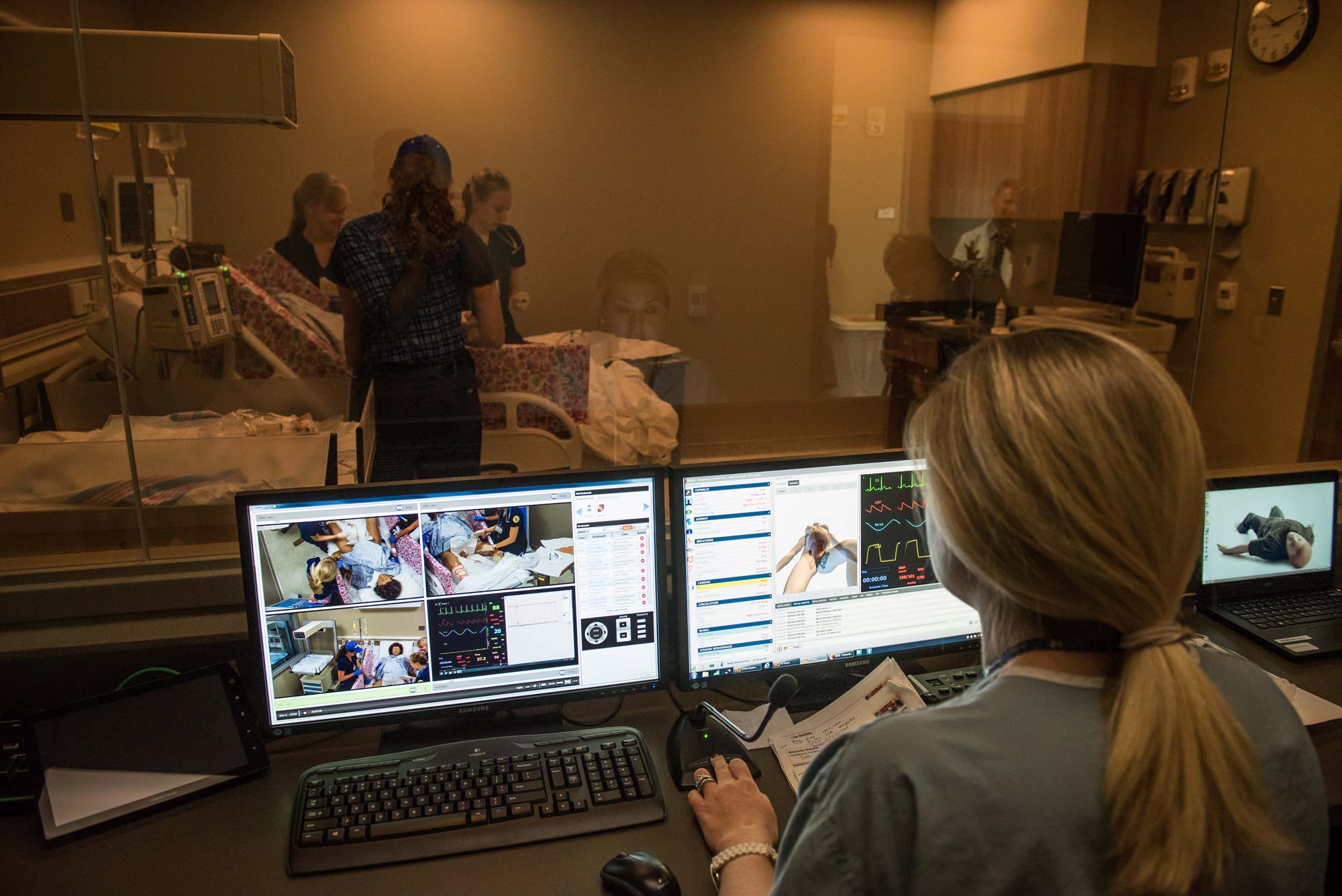 Clinical instructor Maureen Westfall at her control bank behind a one-way mirror in the Clinical Learning Center at the U-M School of Nursing. She operates Victoria wirelessly and students respond to the various medical conditions she presents. Image credit: Michigan Photography