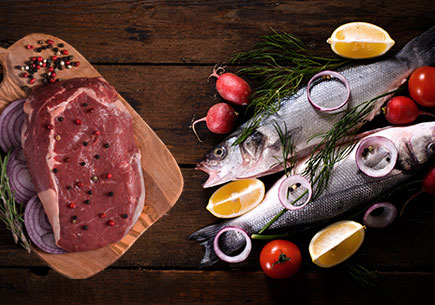 Steak on a cutting board next to a pile of fish. (stock image)