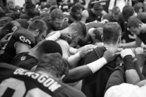 Harbaugh prays with team by David Turnley.
