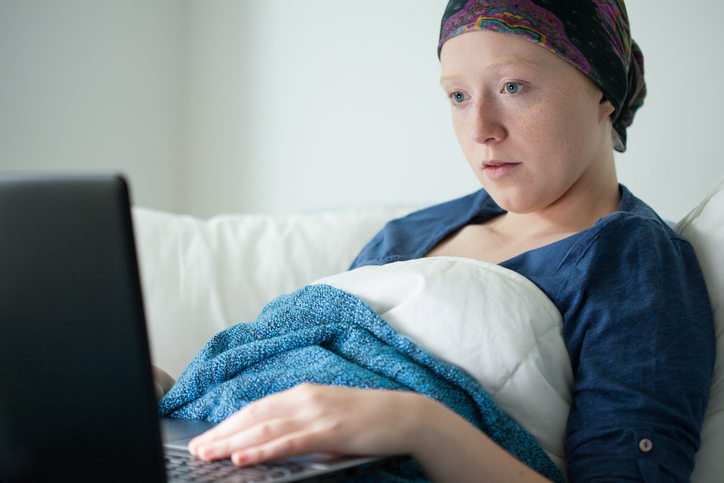 A cancer patient looks at her computer in bed (stock image).