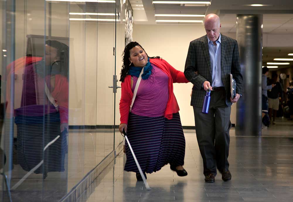 Ypsilanti teen India West, who is visually impaired, and CSE Instructor David Chesney walk down the hall at the Bob and Betty Beyster Building. West worked with Chesney's class to develop technologies for the blind. Photo by Marcin Szczepanski