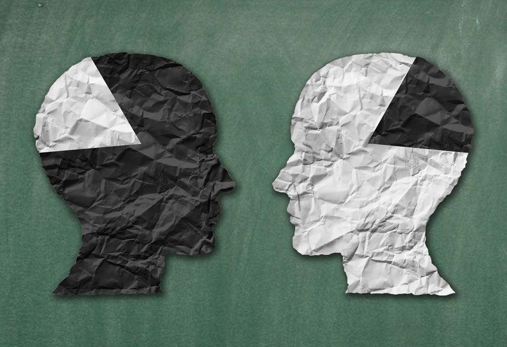 Cut outs of paper heads on top of a chalkboard.