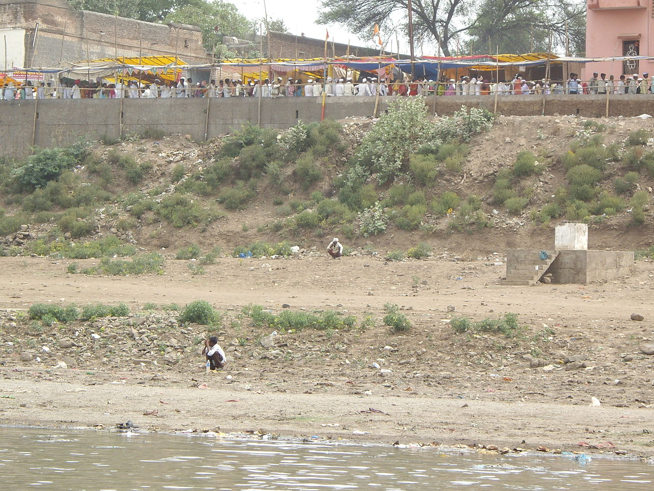 Many people defecate on the banks of the holy river. above is the line to the temple. Image credit: Yaniv Malz via Wikimedia Commons