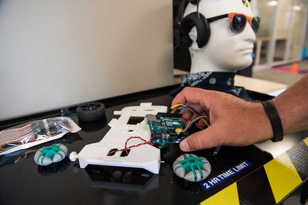 Ramses Alcaide working with a Neurable staffer demonstrates how the technology works to move a Lego Mindstorm toy car by interpreting brain activity at the startup's office space at SPARK in Ann Arbor this summer. Photo by Austin Thomason, Michigan Photography.