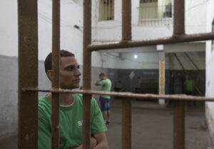 A man sits behind bars in a Brazil prison. Image credit: Levi Stroud