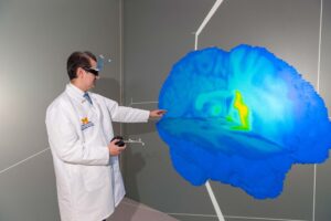 Outfitted with a joystick and special glasses, Assistant Professor Alex DaSilva examines 3D images of the brain to better understand brain chemical fluctuations during a migraine headache. DaSilva is in the Michigan Immersive Digital Experience Nexus, or MIDEN, on North Campus. Images credit: Scott Soderberg, Michigan Photography