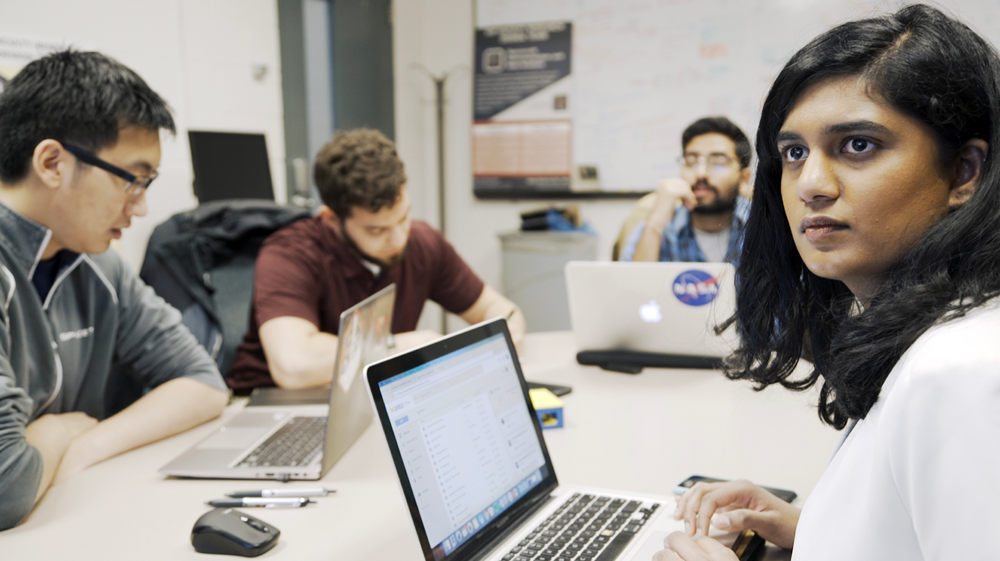 University of Michigan M-BARC team lead Hashmita Koka, a graduate student in aerospace engineering, discusses orbital dynamics of their satellite time capsule with other members of the group. Image credit: Robert Coelius
