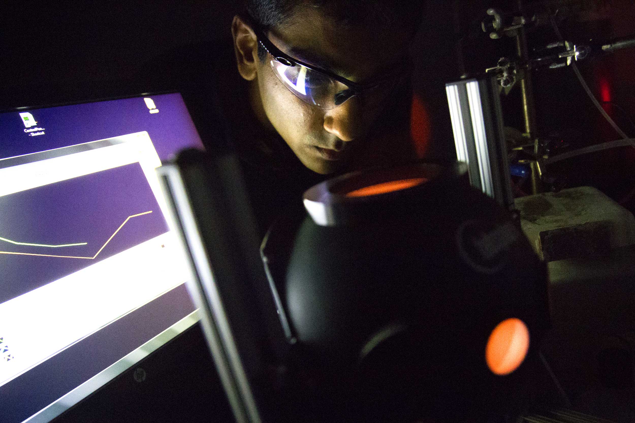 Umar Aslam peers into the light source used during the experiments that revealed how the silver nanocubes captured energy and delivered it to the platinum shells. Image credit: Akhil Kantipuly, Michigan Engineering