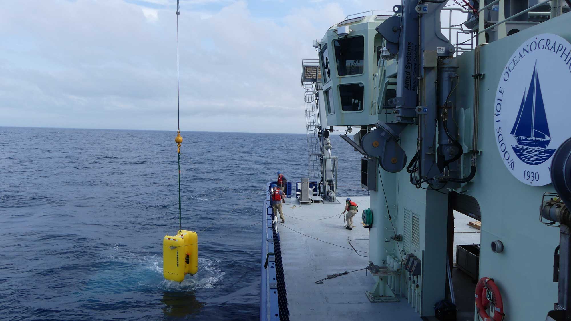 The crew aboard the R/V  Neil Armstrong  helps guide  Clio  into the water for tests at  sea. During the expedition , Clio  completed five dives, including two dives to 2,000  meters (1.2 miles), and filtered more than 1,000 liters (264 gallons) of se awater  from nine different depths. Image credit: Mak Saito, Woods Hole Oceanographic Institution