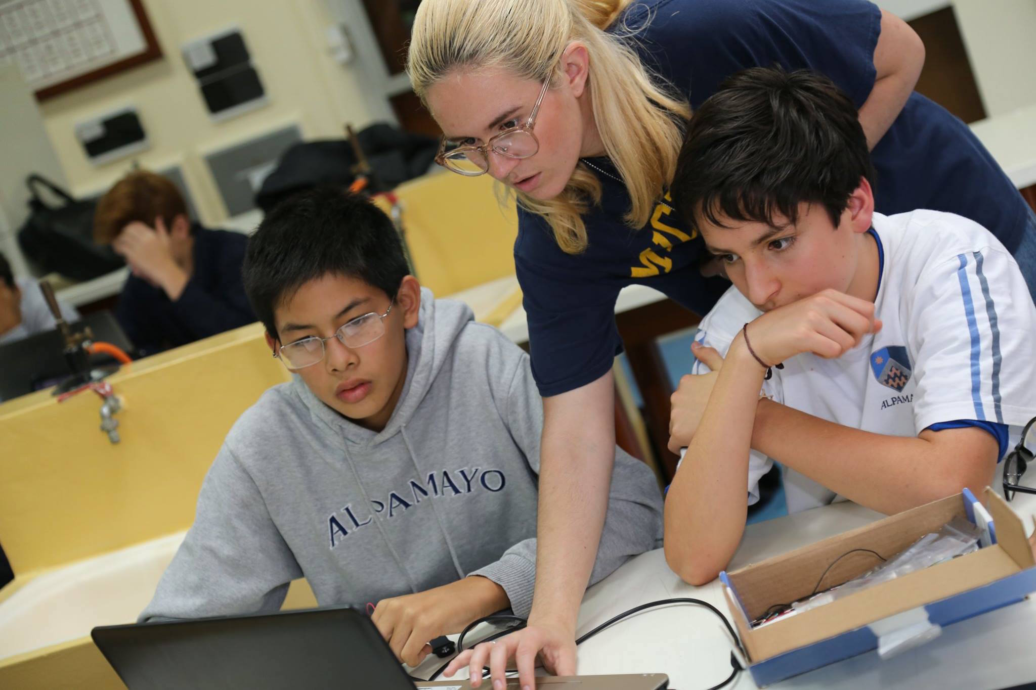 University of Michigan student Isabella DeShantz working with high school students from Alpamayo school to do a python programming project.
