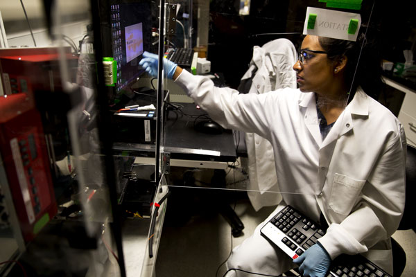 Stacy Ramcharan, a doctoral student in chemical engineering, uses a computerized system to layer polymer fibers, forming a scaffold for growing cells into artificial tissues. Photo: Joseph Xu, Michigan Engineering Communications & Marketing.