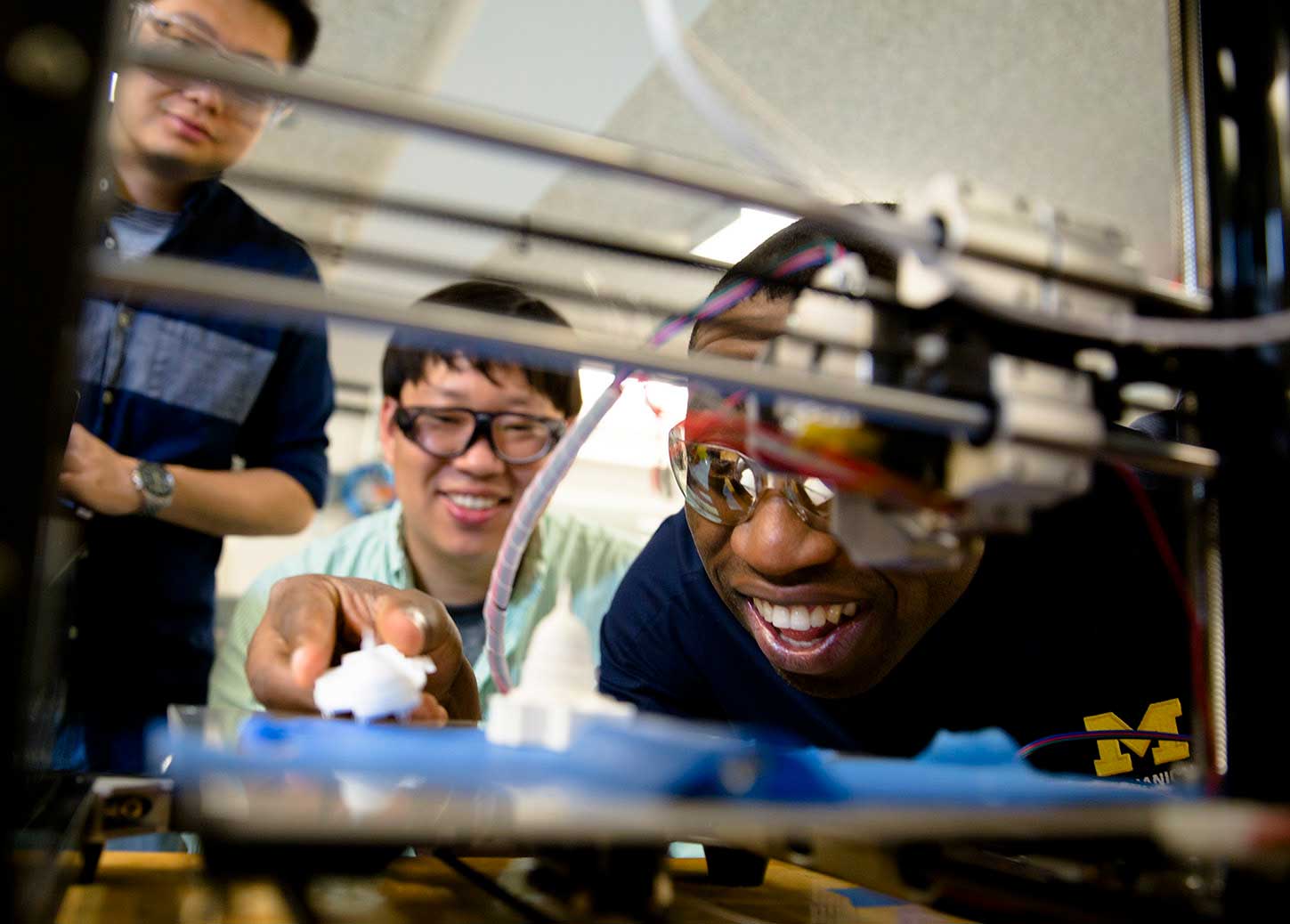 Molong Duon and Deokkyun Yoon, both mechanical engineering PhD students, and Chinedum Okwudire, associate professor in mechanical engineering, examine the effectiveness of their new, faster 3D printing algorithm. Image credit: Evan Dougherty, Michigan Engineering
