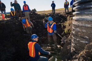 U-M paleontologists Michael Cherney, left, and Daniel Fisher dig for mammoth bones next to a sump pump at a low point in one of farmer James Bristle’s fields. Installation of the drainage system led to the discovery of mammoth bones in 2015.