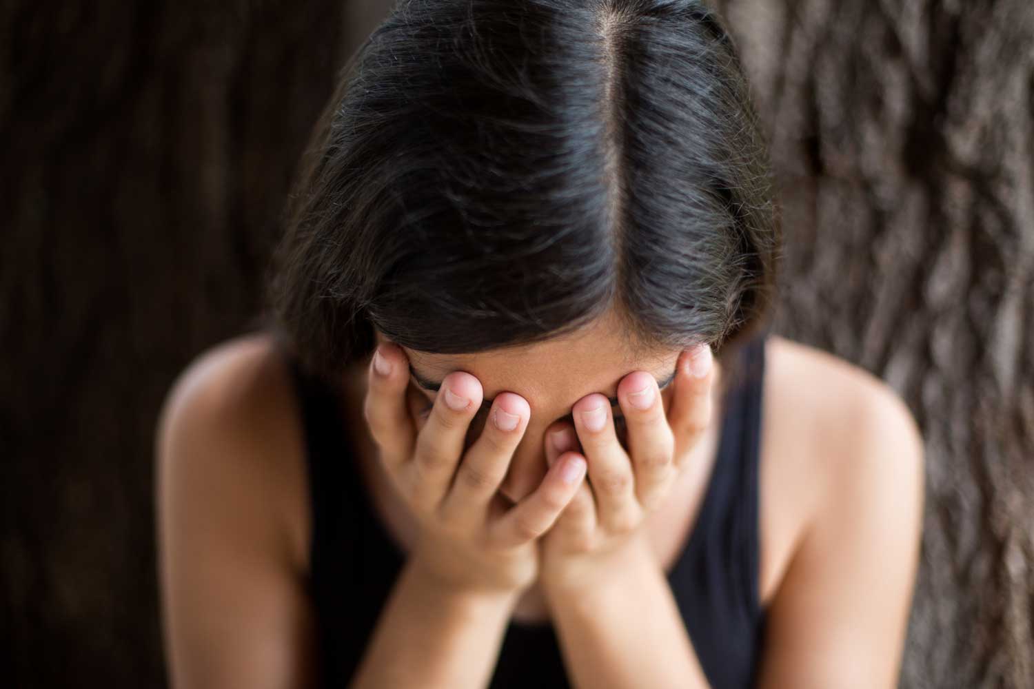 A woman holds her face in her hands. (stock image)