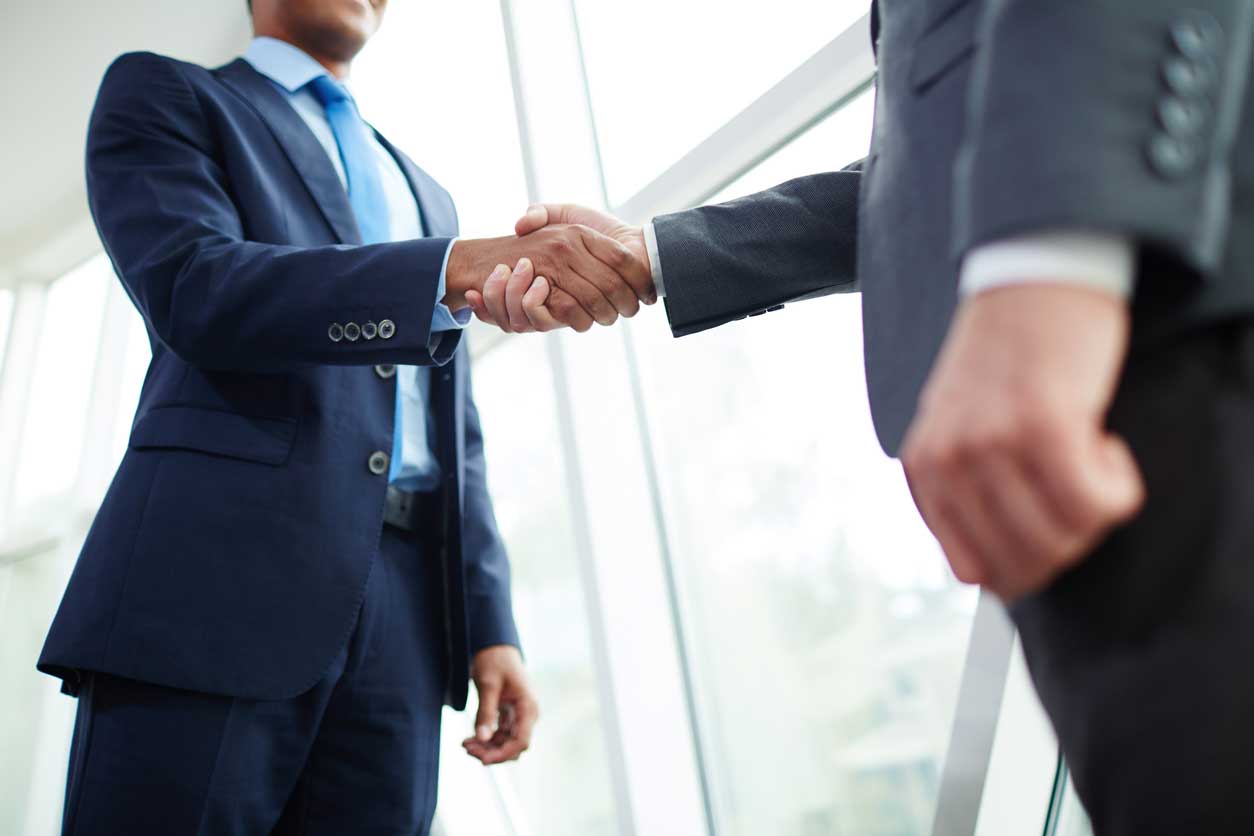 Two people in suits shaking hands. (stock image)