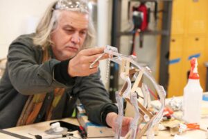 Chico MacMurtrie holds a prototype of the “Border Crosser” at the University of Michigan’s Wilson Student Team Project Center. Image credit: Robyn Han