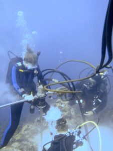 Diane Thompson, left, drilling a Porites lobata coral colony near Wolf Island, in the Galapagos. Thompson is assisted by Sandy Tudhope, center, and Roby Pepolas, right. Image credit: Jenifer Suarez, courtesy of the Cole lab
