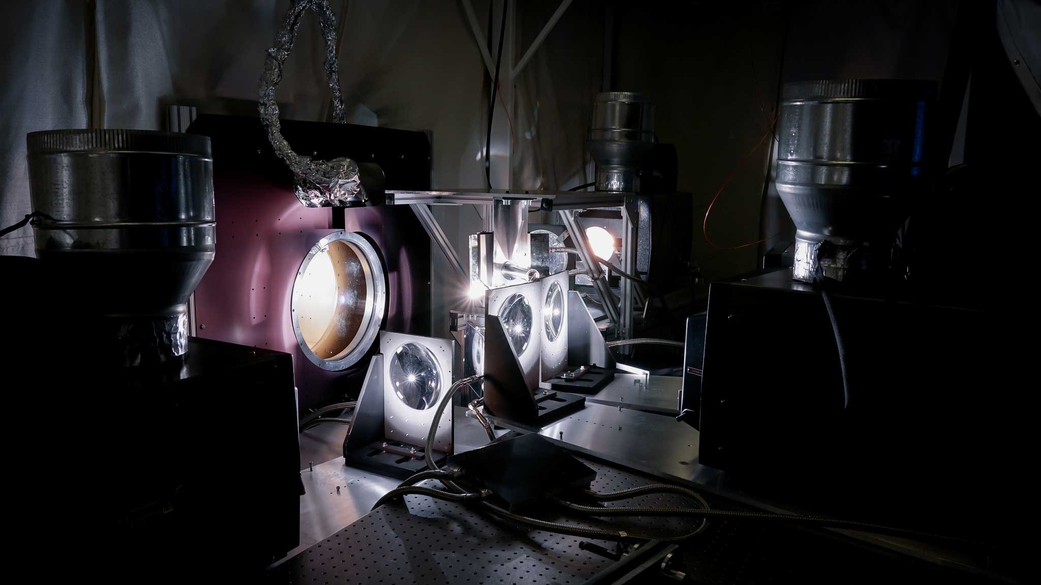 Researchers use a quartet of IMAX projectors to create the light and heat the Parker Solar Probe cup will experience during its trips through the sun's atmosphere. The cup sits inside a vacuum chambers set up in a lab at the Smithsonian Astrophysical Observatory in Cambridge, Massachusetts. Image credit: Levi Hutmacher, Michigan Engineering