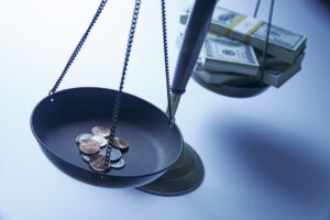 A stack of cash and a stack of pennies on a scale.