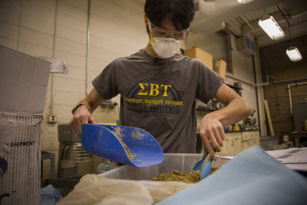 Isaya Miyata, undergraduate in civil and environmental engineering, prepares Ultra High Performance Concrete. UHPC is a new class of concrete that utilizes a low water content as well as steel fibers mixed in for extra density. Once set, the concrete is able to take on 6-7 more impact load than regular concrete before it fails. While UHPC is more expensive than regular concrete, the cost savings using this stronger, longer-lasting concrete could be significant. Image credit: Robert Coelius, Michigan Engineering