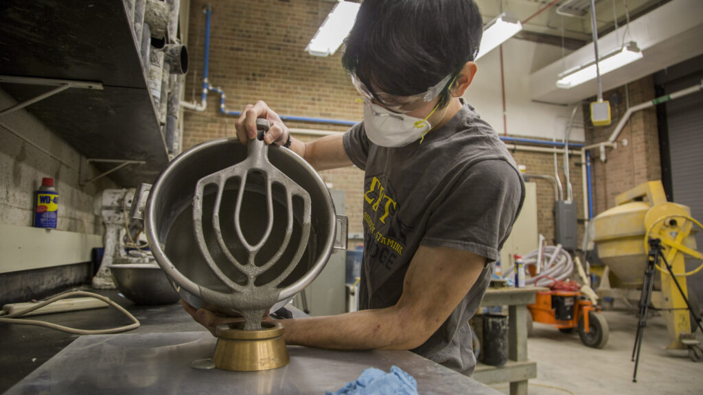 Isaya Miyata pours the concrete formula into a mold. Image credit: Robert Coelius, Michigan Engineering