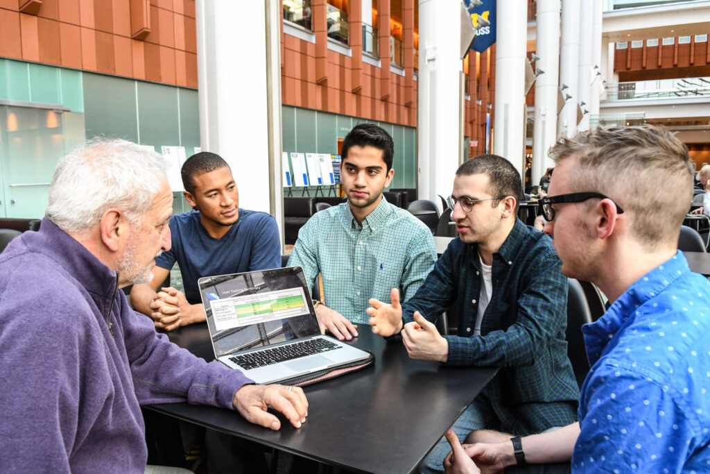 Students Tristan Neeb, Aklavya Kashyap, Shayan Shafii and Sean Dew talk about next steps with their instructor, Robert Pasick of the Ross School, on the goal tracking voice assistant they created for use with Amazon's Alexa. Image credit: Randy Maschaka
