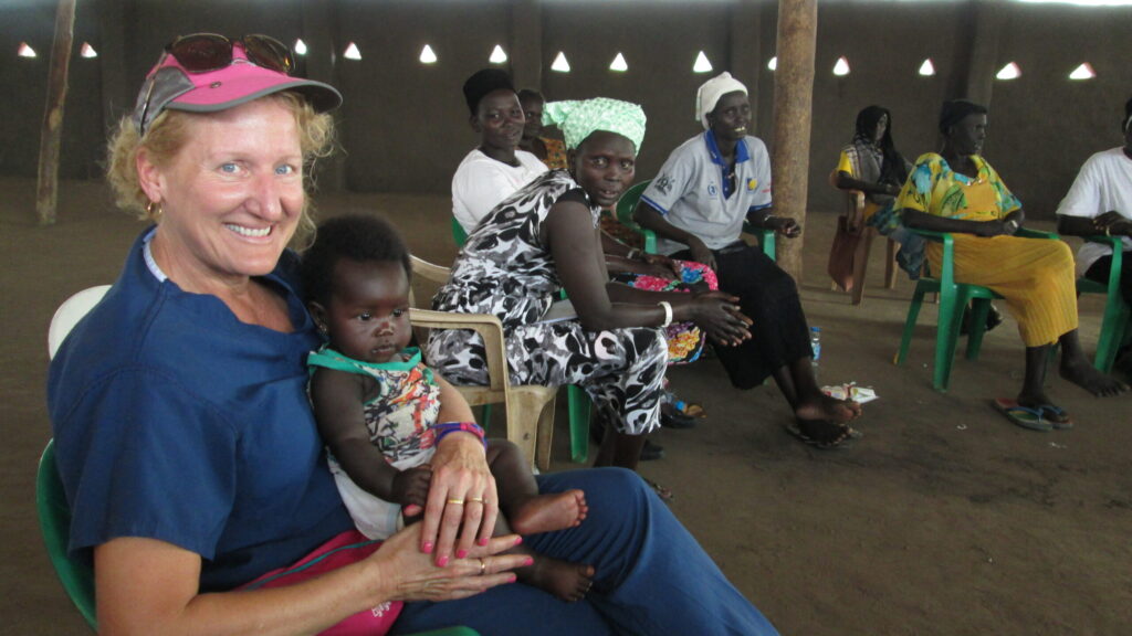 Ruth Zielinski, associate professor in the U-M Nursing School, holds a baby whose mother is taking Zielinski’s class on family and child health in a Ugandan refugee camp.