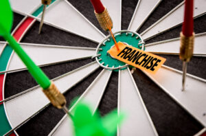 Dartboard with paper reading "franchise" in the middle 