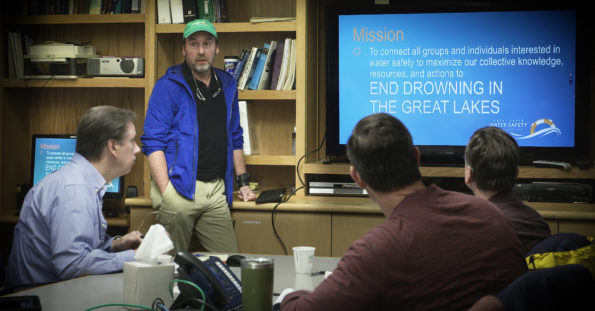People sitting around a table as a man presents on water safety mission