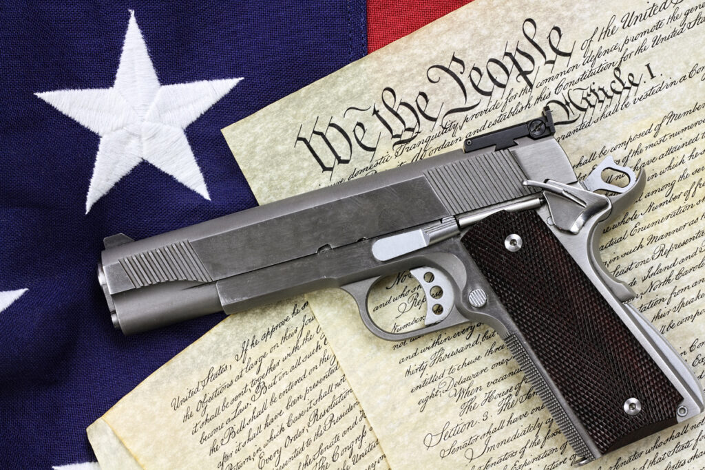 Handgun lying over a copy of the United States constitution and the American flag. (iStock image)