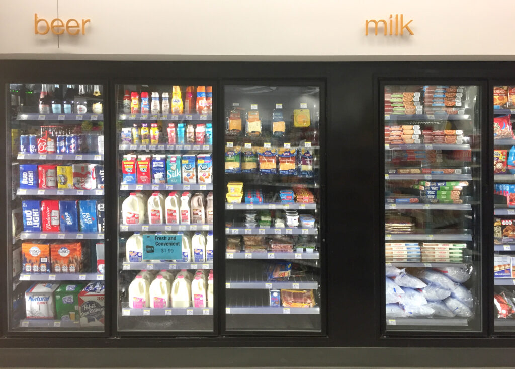 A convenience store refrigerator stocked with dairy products and alcoholic beverages. Image credit: Hans Anderson